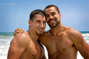 smiling gay male couple on a beach