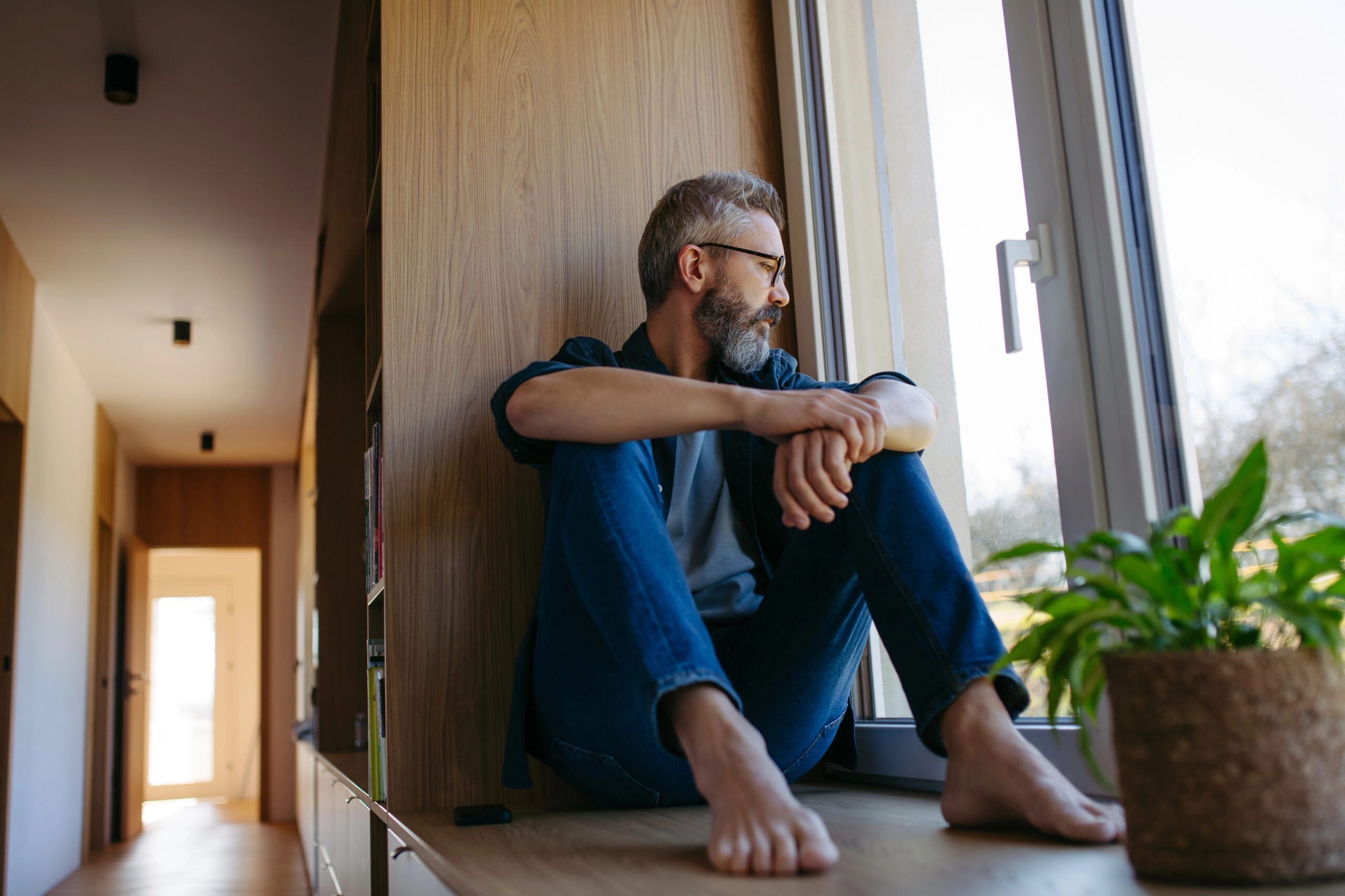 Man sitting beside a window in a quiet room.